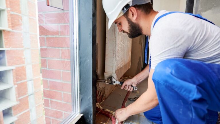 Instalator montuje na ścianie grzejnik dekoracyjny