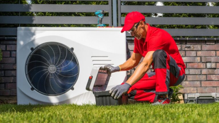 Instalator montuje pompę ciepła w ogrodzie przed domem